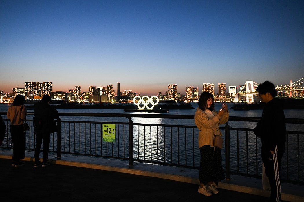 周三，人们在东京的奥运五环前拍照。就在前一天，由于新冠病毒的威胁，日本官员将今夏的奥运会推迟到明年举行。