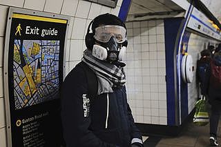 2020年3月18日，一名男子戴上防毒面罩，在国王十字（King’s Cross）地铁站月台候车。（美联社）