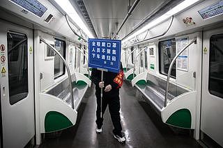 3月28日，武汉地铁恢复运营。工作人员在车厢内提醒乘客防疫措施。（Getty）
