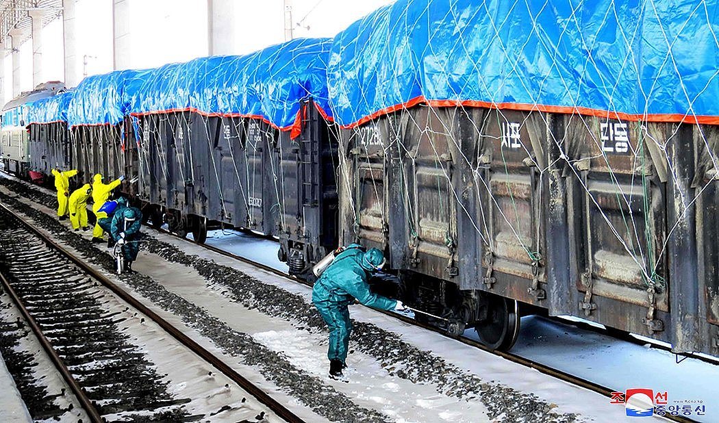朝鲜官方媒体本月发布的一张照片显示，在中朝边境的新义州，工人们给一列货运列车消毒。