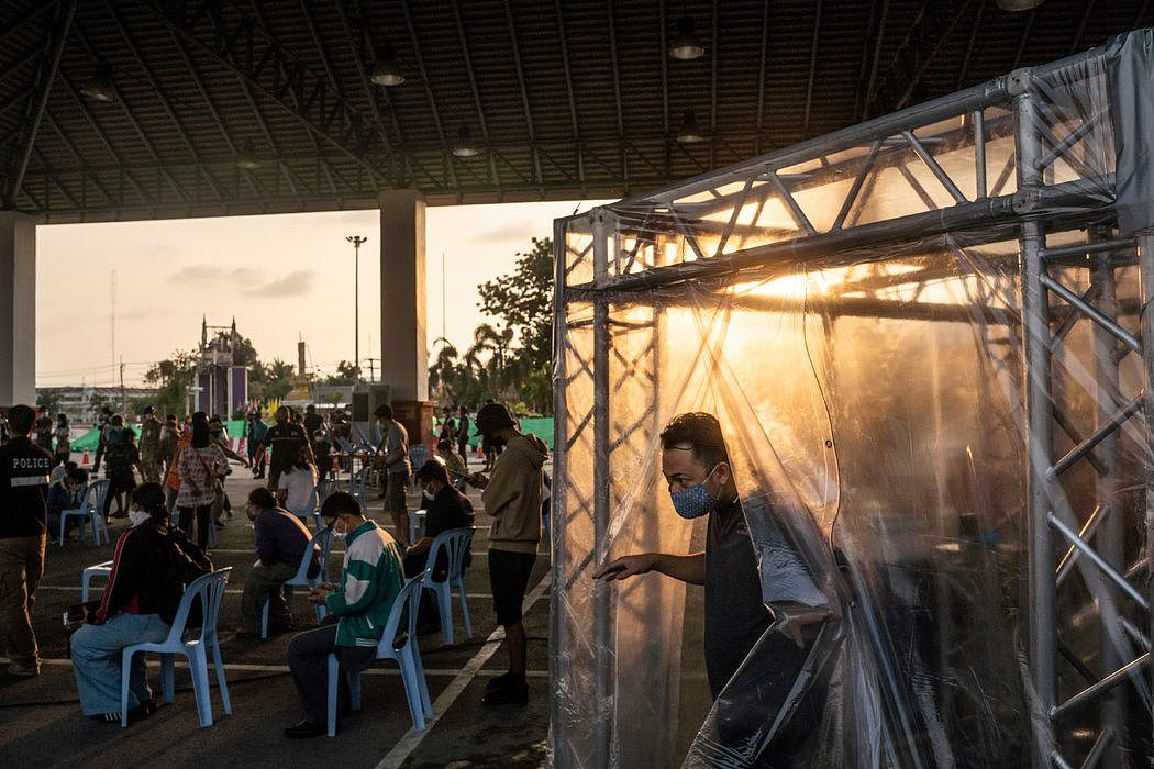 周二，泰国当局在普吉岛一个检查站的洗消帐篷里向旅客喷洒消毒剂。