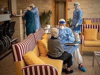 4月1日，来自西班牙非政府组织“张开双臂”的一名救援人员在西班牙巴塞罗那的一家养老院，与一名老年妇女进行测试前的交谈。（AP）