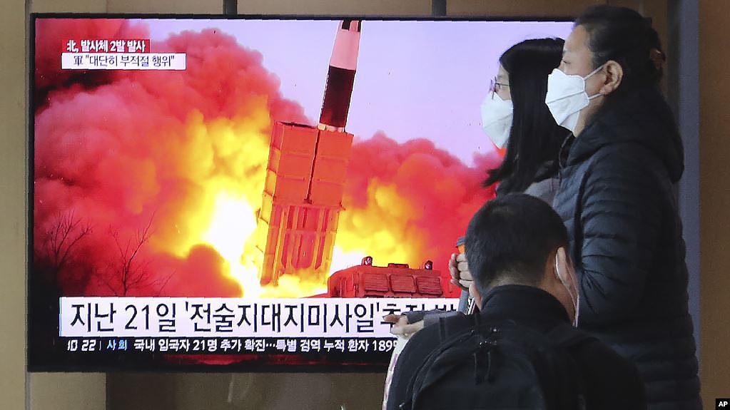 在韩国首尔火车站，人们经过一个电视屏幕显示新闻节目播出朝鲜发射导弹的画面(2020年3月29日)