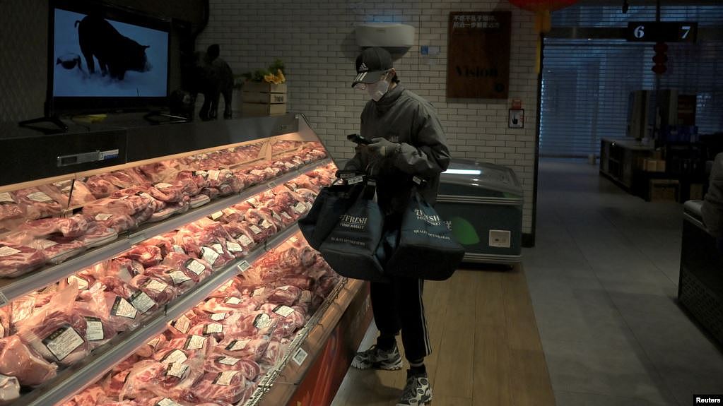 一名戴着口罩的互联网供货商在北京亦庄一家肉店为网上订户购买猪肉。（2020年2月8日）