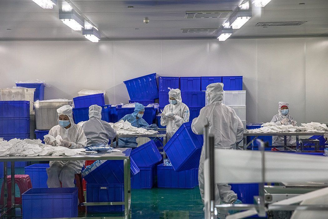 在冠状病毒最早出现的中国武汉，一家医疗器械工厂的员工正在整理防护口罩。