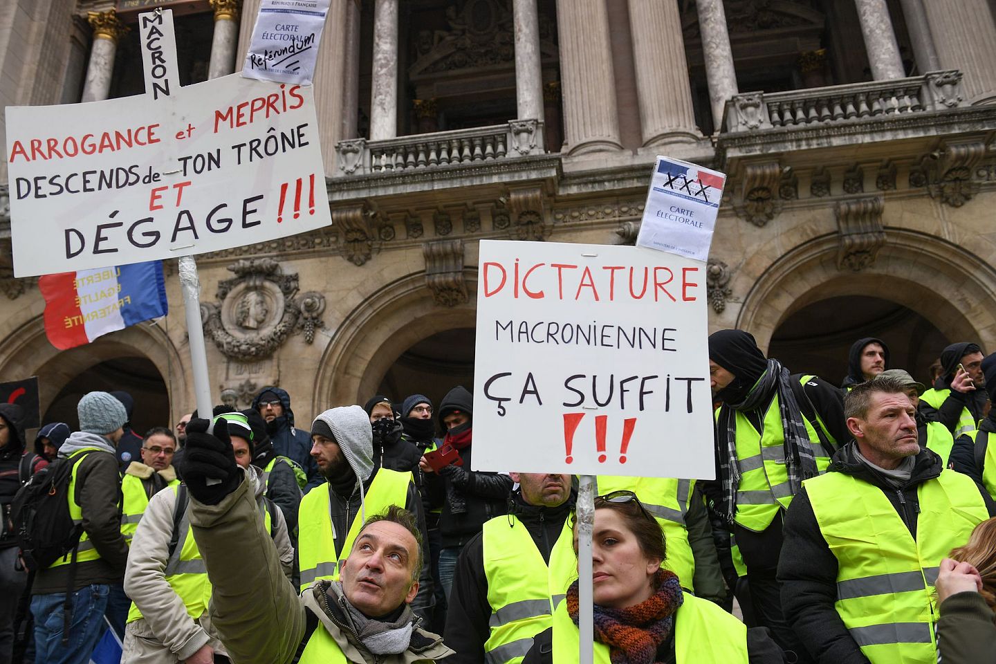 2018年12月15日，法国巴黎，抗议者在黄背心示威活动中手持标语牌，呼吁结束马克龙的总统任期（“傲慢和鄙视，落下你的宝座，滚出去”）。(Getty)