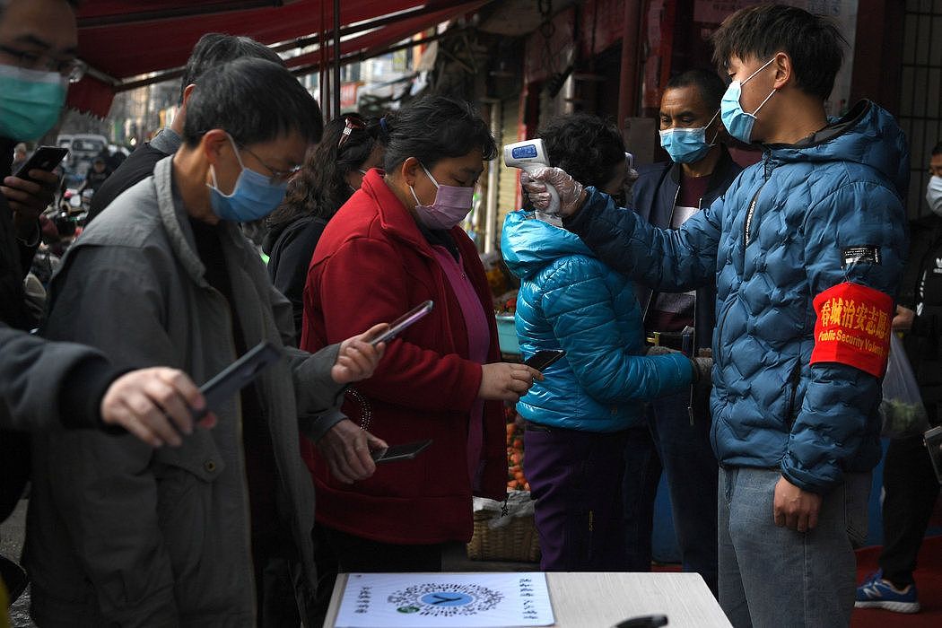 位于中国南方的云南昆明，人们在进入市场前要用手机扫码，与此同时，志愿者检测他们的体温。