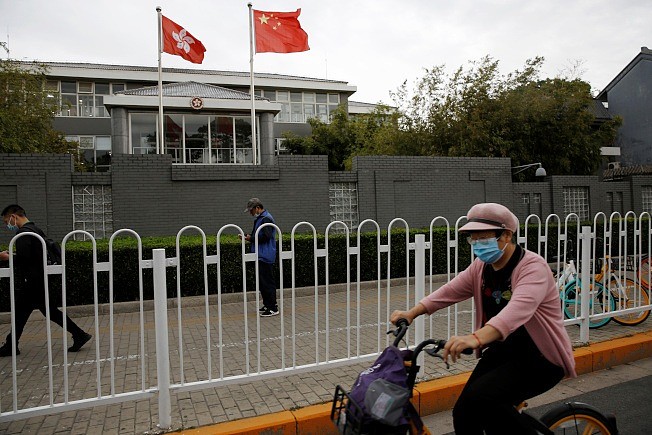 正在北京举行的中国人大会议，将于28日审议表决港版国安法。 图为戴口罩的民众经过香港行政特区政府在北京的办事处。 (路透)