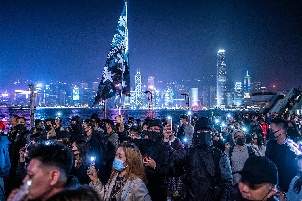 去年平安夜尖沙咀的抗议者，远处是香港独特的天际线。
