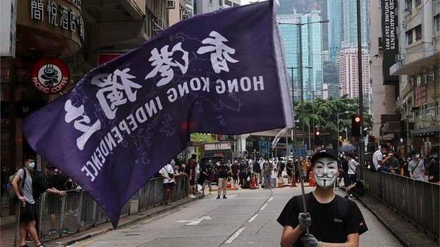A masked anti-government protester holds a flag supporting Hong Kong independence during a march against Beijing