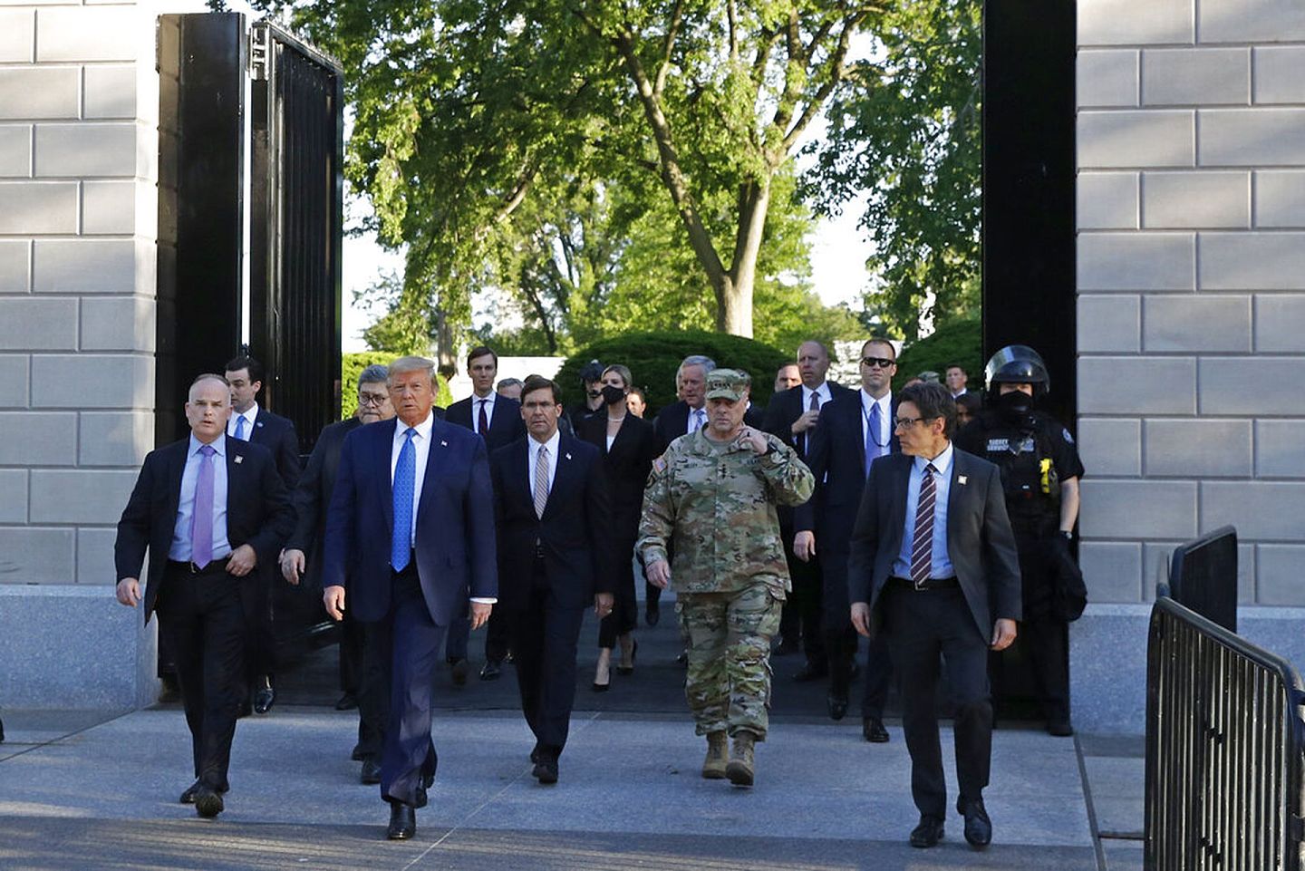 特朗普在一群幕僚与保安人员拥护下走出白宫。（美联社）
