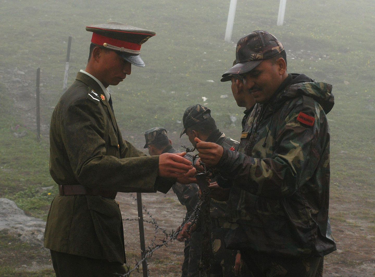 当地时间2006年7月5日，中印边境乃堆拉山口，一名中国军人（左）和印度士兵一起试图把篱笆系好。（Getty）