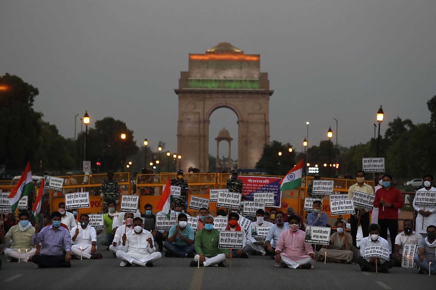 6月17日，印度执政党印度人民党成员坐在新德里的“印度门”纪念碑前，手持蜡烛，向在拉达克地区与中国士兵对峙中丧生的印度士兵致敬。用当地语言写着的横幅上写着：“印度母亲呼吁采取有力行动，中国要理智不要惹印度。”（AP）