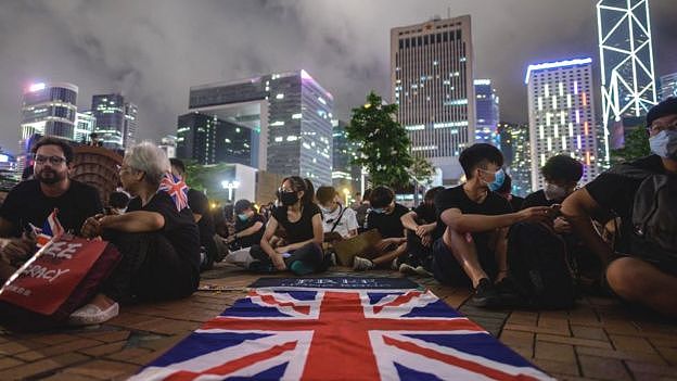 A British Union Jack flag is displayed as protesters gather along a fenced-off Victoria Harbour pier in Hong Kong
