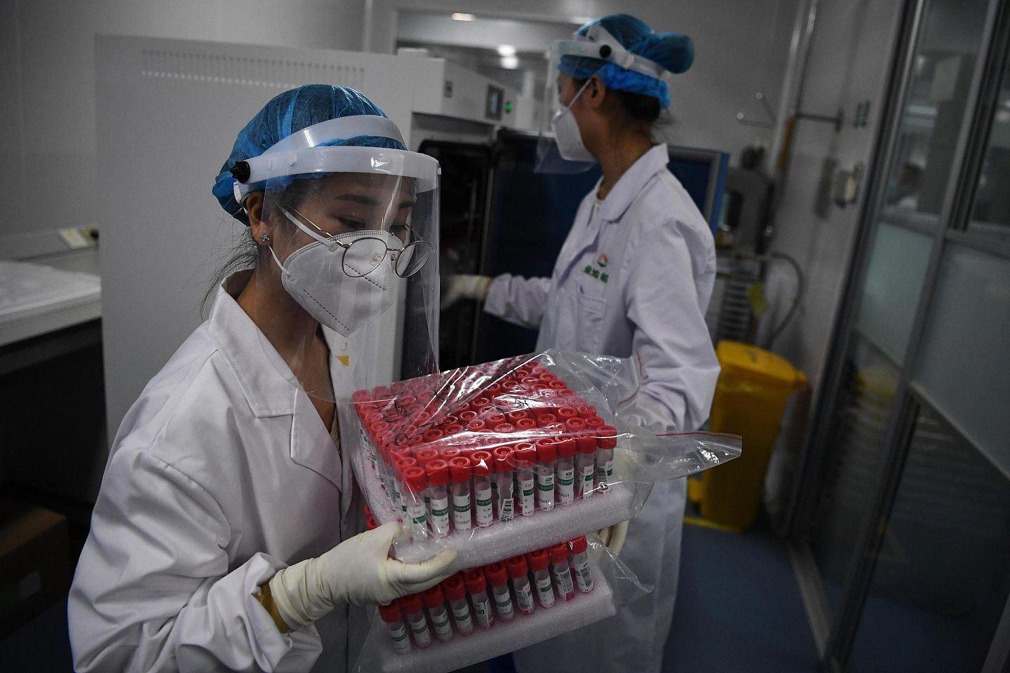 6月25日晚，北京的检测人员正在从仪器中取出经过干灭活的核酸检测样本。（人民视觉）