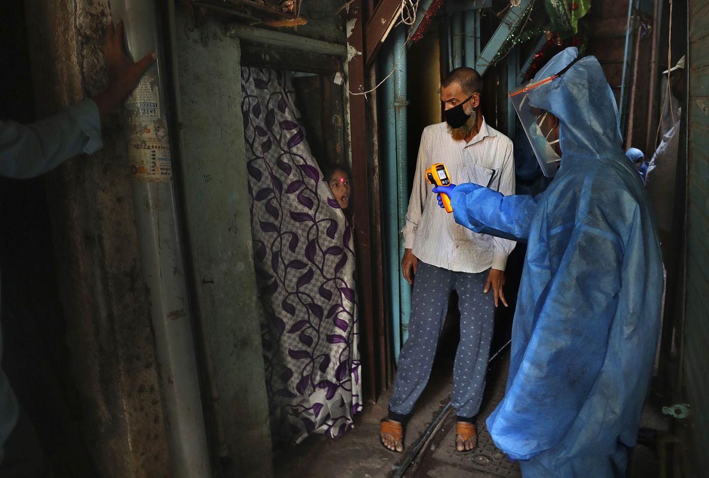 在孟买达拉维贫民窟中，医生为一个女孩测量体温。（AP）