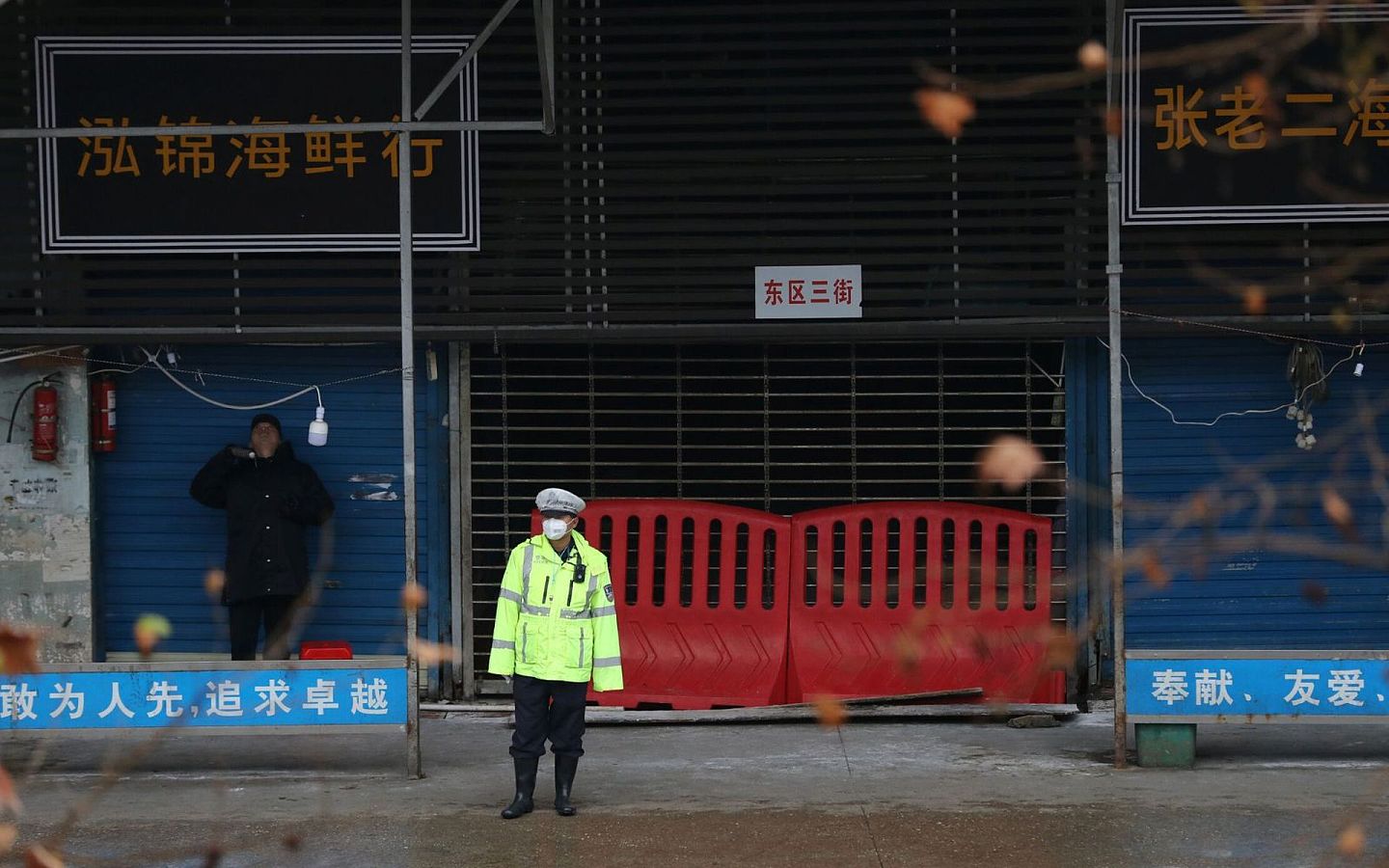 武汉华南海鲜市场曾被认为是最早出现新冠病毒的场所。图为2020年1月10日，一名戴着口罩的警务人员站在中国湖北省武汉市封闭的海鲜市场前。（路透社）