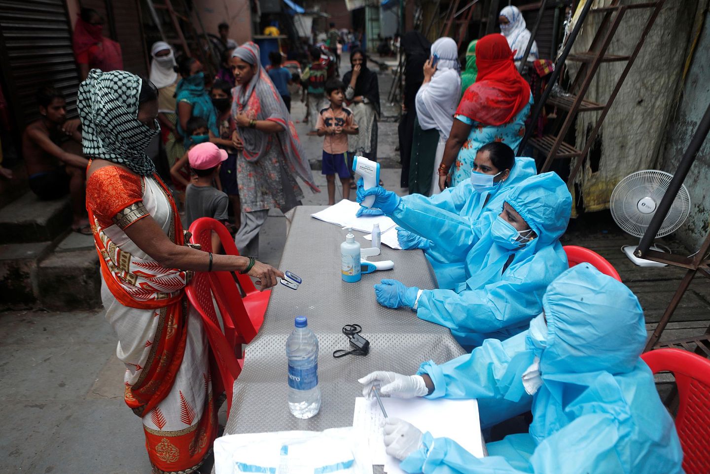 2020年6月30日，印度孟买贫民窟，医护人员在检查居民的体温。（Reuters）