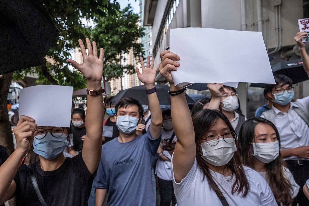 上周五，一名被拘抗议者的支持者们在法院外举着无字标语。