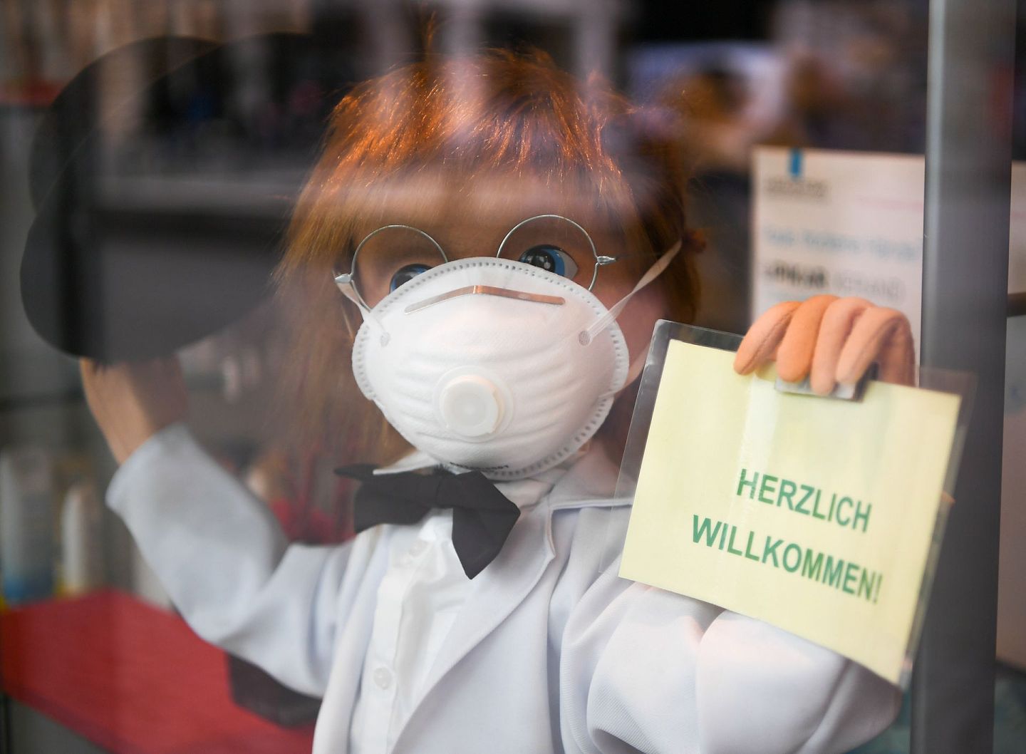 随着疫情在全球多地爆发，口罩等医疗物资重要性不言而喻。图为3月8日，在德国法兰克福，一家药店门口摆放着戴口罩的卡通人偶。（新华社）