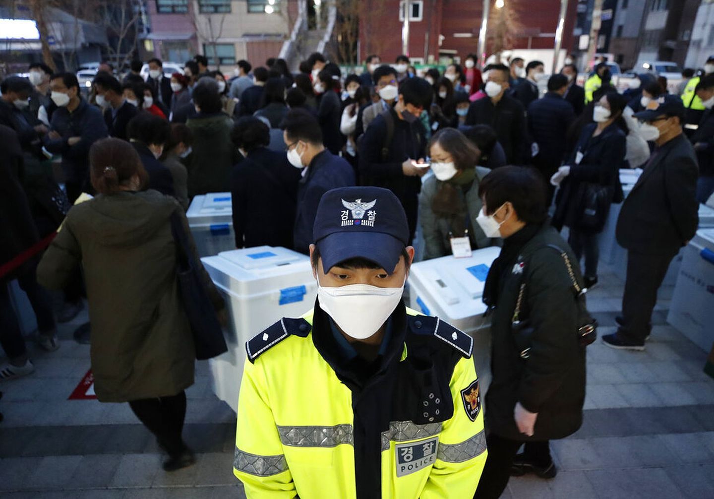 4月15日，韩国一名戴着口罩的警员在国会选举一个点票站站岗。（AP）