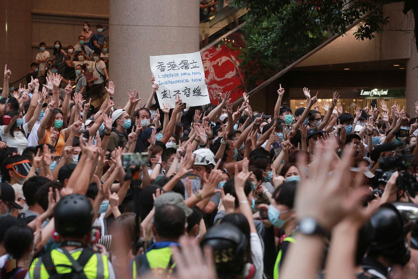 在一次集会游行中，一些香港巿民举起“五大诉求，缺一不可”手势，人群有人举起港独标语。（HK01）