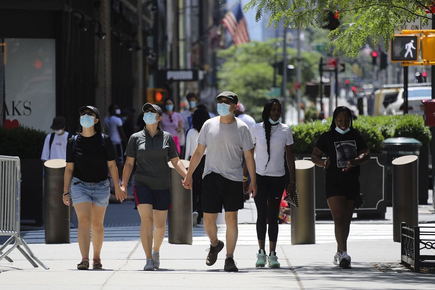 美国多地疫情仍面临严峻形势，人们戴着口罩走在纽约第五大道。（新华社）