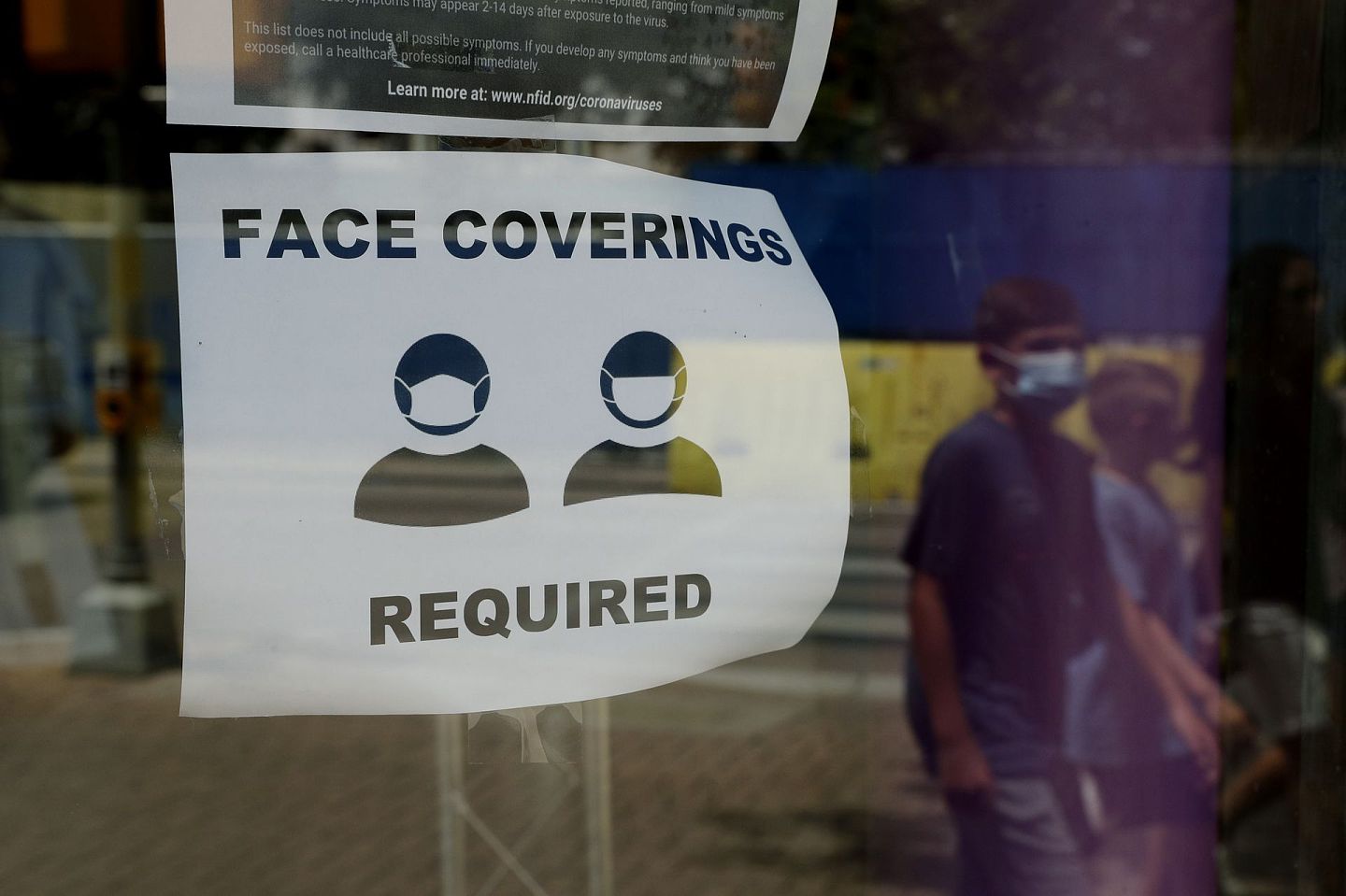 7月7日，美国圣安东尼奥一名戴着口罩的游客通过一个要求佩戴口罩的指示牌。（AP）