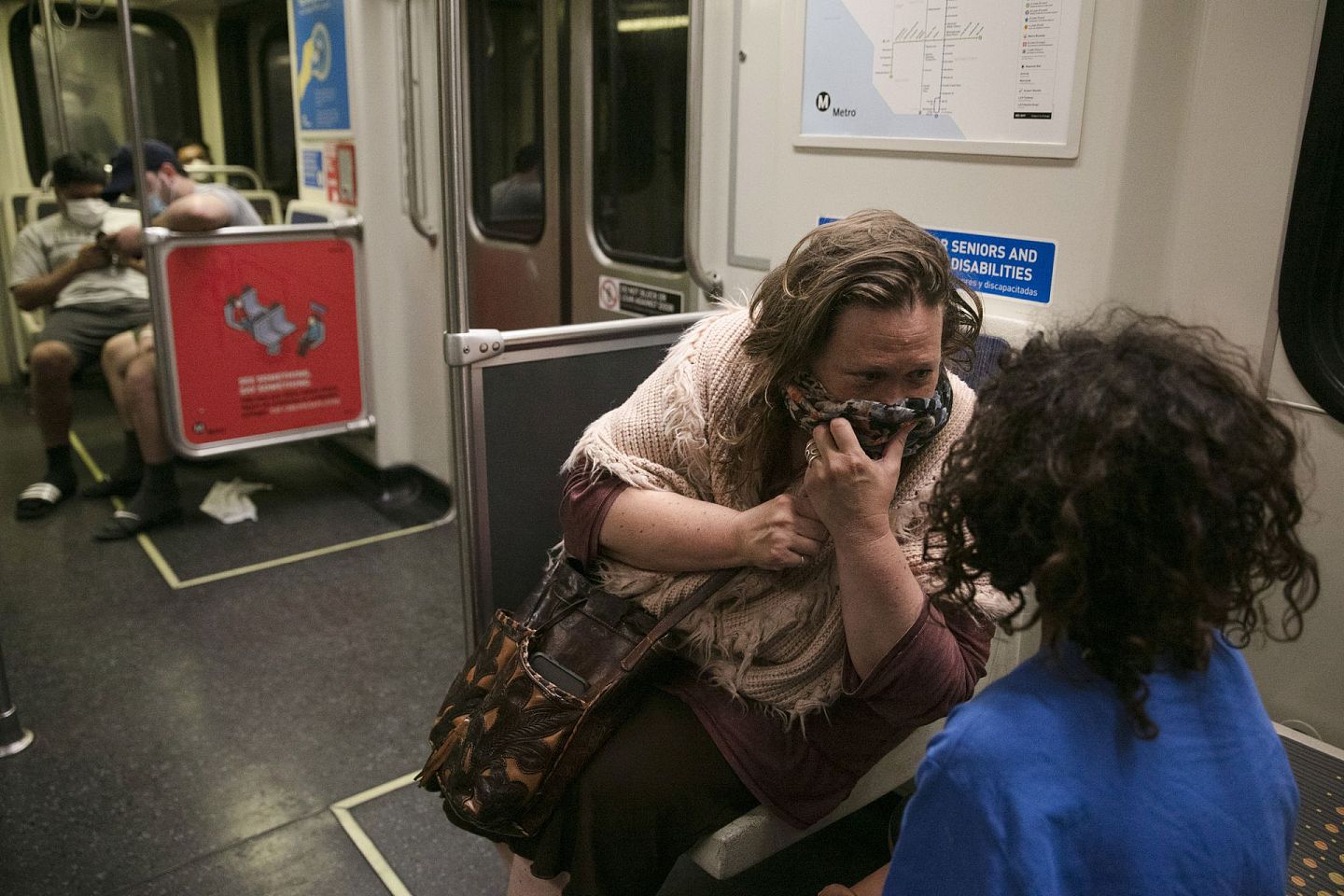 7月6日，洛杉矶女子丽莎·芬克在地铁上和儿子阿尔说话时掩住口鼻。（AP）