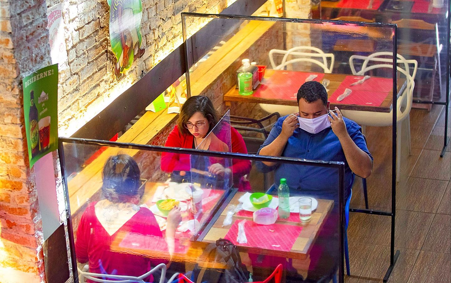 圣保罗一间餐厅用塑料隔壁把每张桌子隔开，图为人们7月6日在这间餐厅进食午餐。（AP）