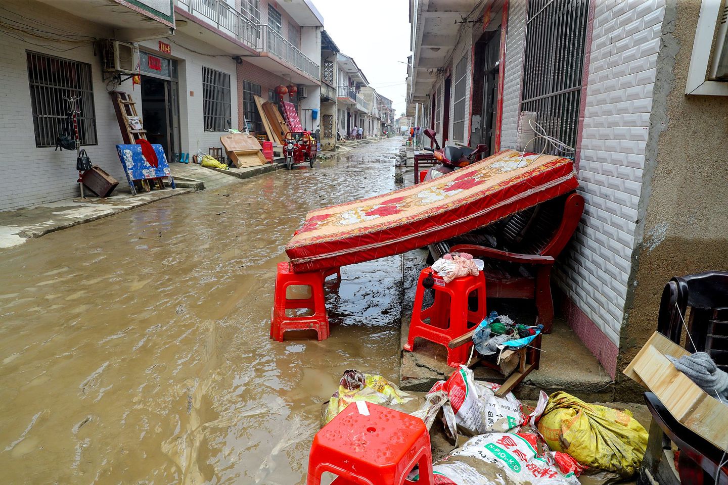 7月9日，在洪水退去后的湖北黄梅县濯港镇桂壩村，村民家门口摆放了搬出的床垫。（中新社）
