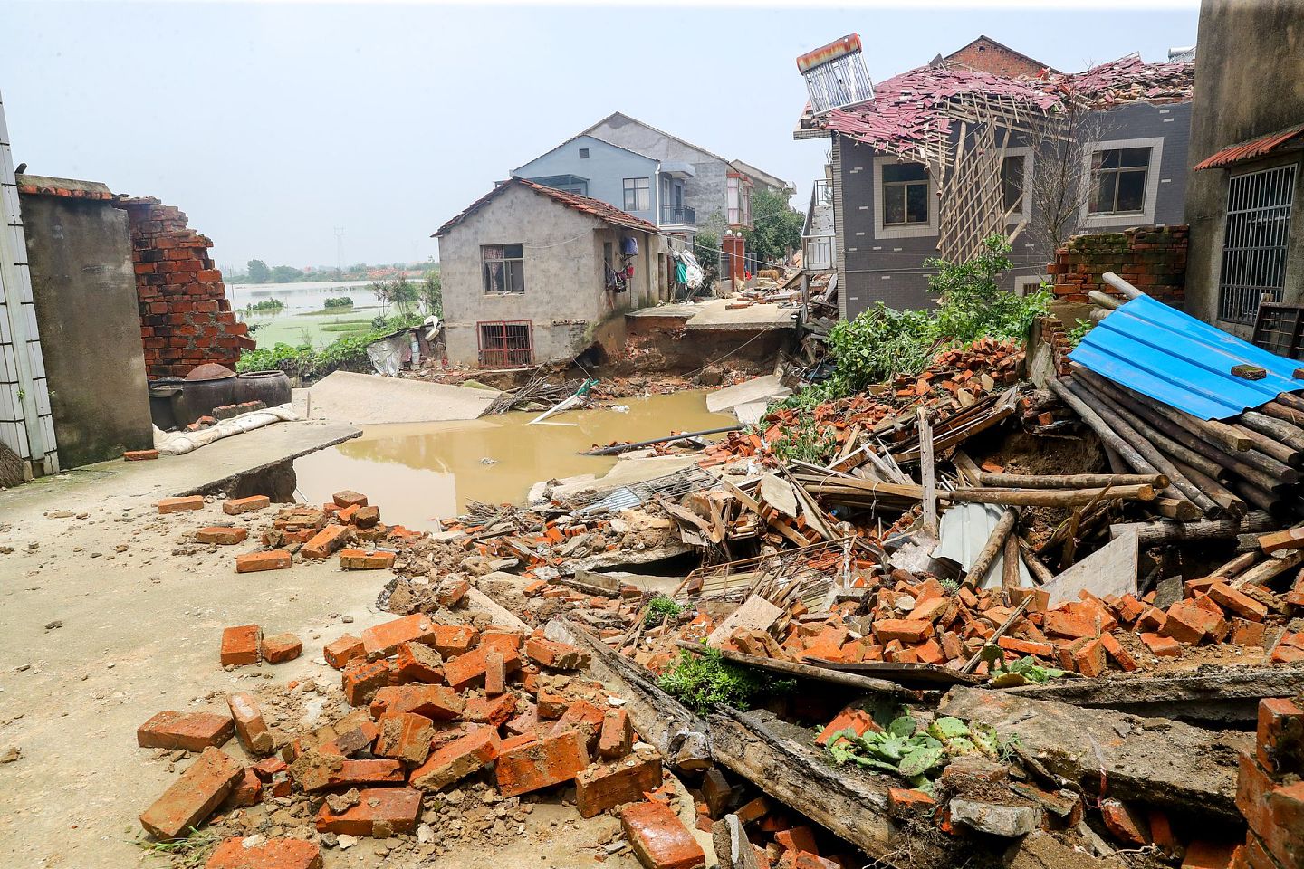 7月9日，在洪水退去后的湖北黄梅县濯港镇桂壩村，道路和房屋被洪水冲毁。（中新社）