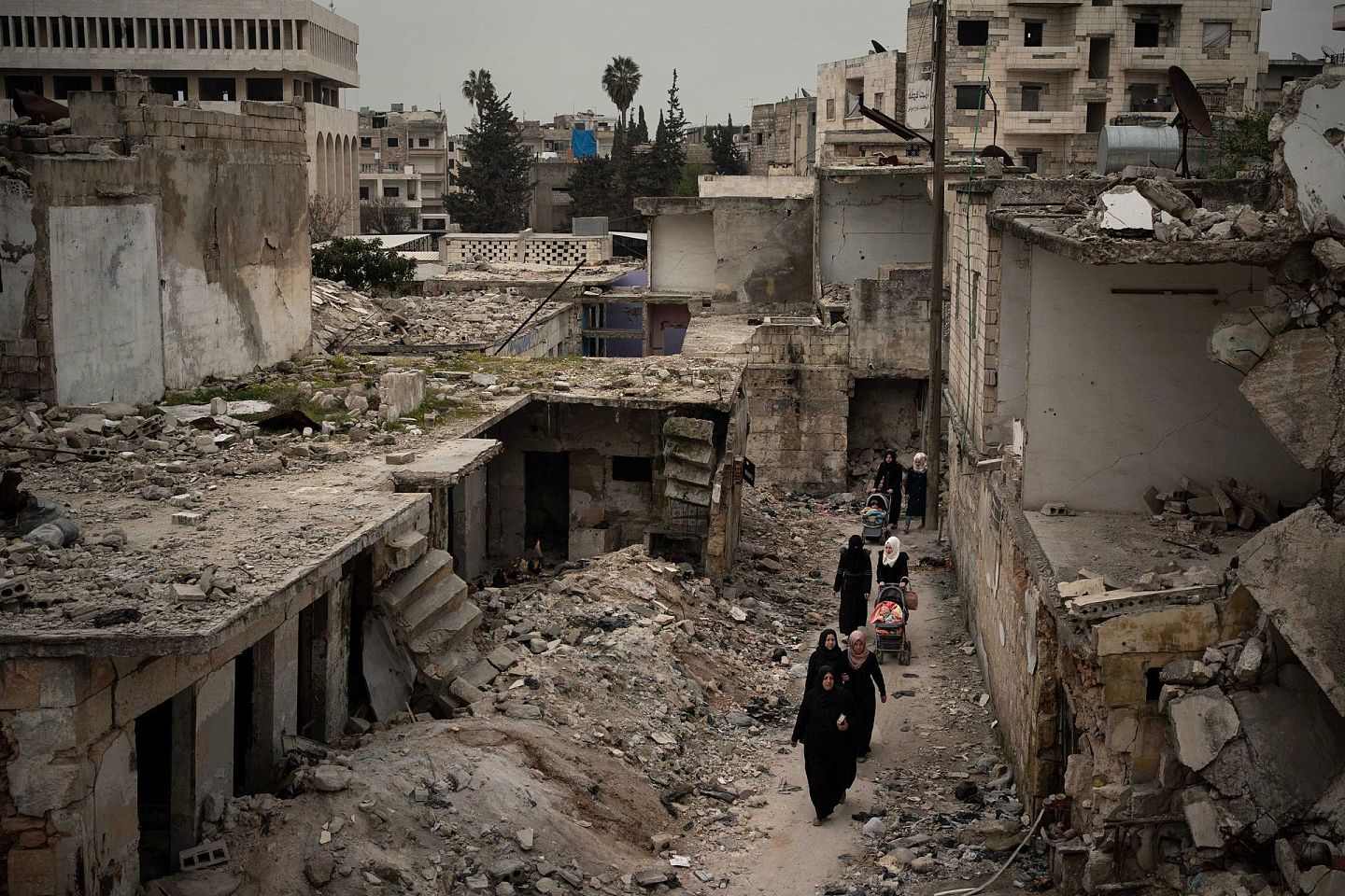2020年3月12日，妇女们走在叙利亚伊德利卜被空袭严重破坏的社区道路上。（AP）