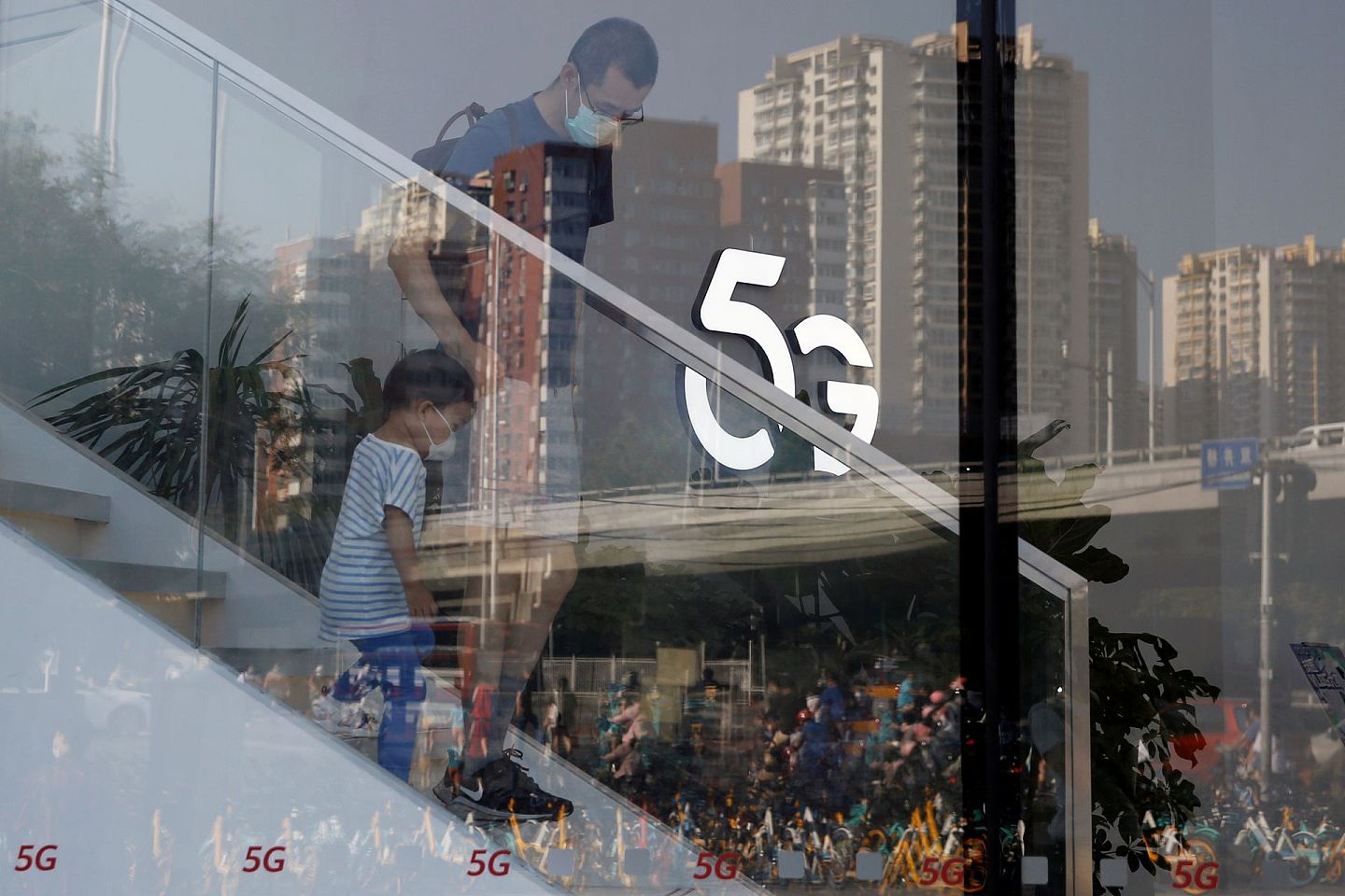 图为2020年7月14日，中国北京一间华为商店有戴口罩的民众经过5G标志。（Reuters）