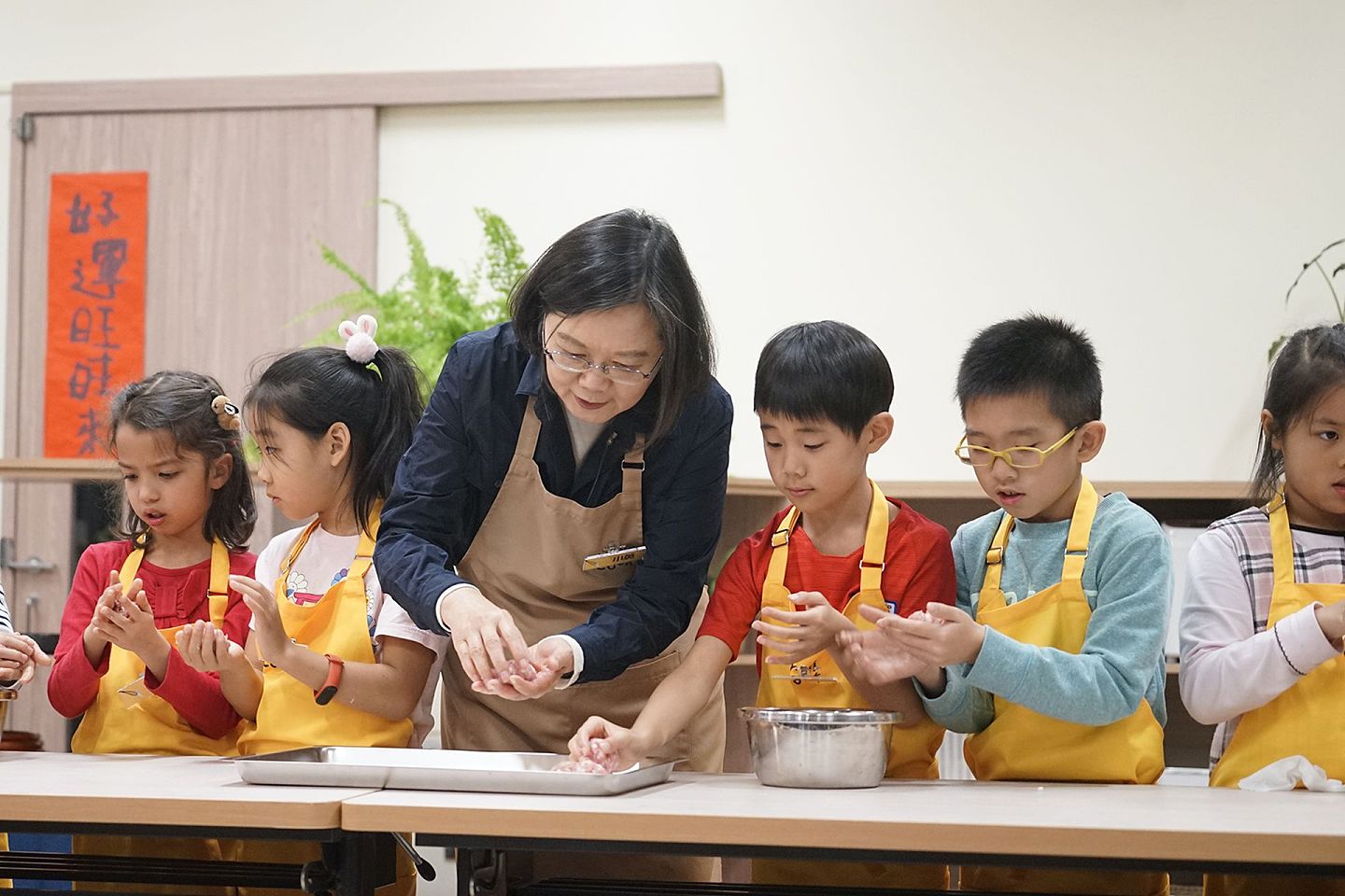 小学生对民进党未来的支持度具有重要影响，图为2019年蔡英文到台北市立和平实验国民小学与一群“迷你厨师”，在学校厨房一同做年菜，展现其亲民一面。（多维新闻）