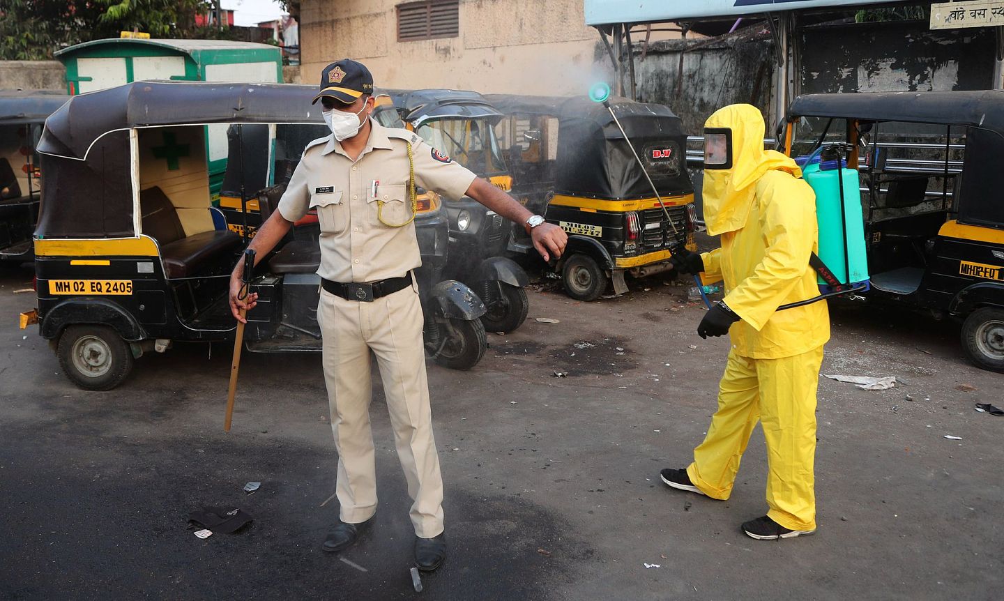 在印度孟买的贫民窟，由于当地疫情严重，市政工人以向站岗的警察喷洒消毒剂方式为其直接“消毒”。在孟买，当地警队也是新冠疫情的重灾区。（美联社）