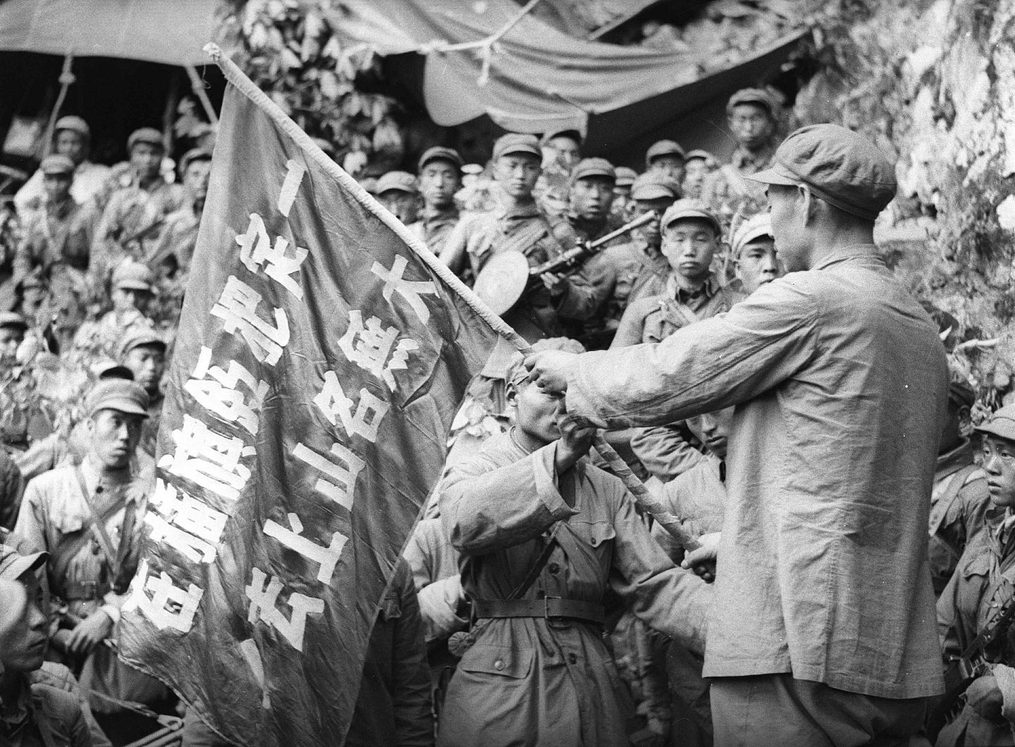 1953年6月10日，中国志愿军某部在强大炮火配合下，向固守在八八三`八高地的南朝鲜军发起猛烈攻击，最终歼敌一个团的大部，全部占领了敌人阵地。这是出征誓师大会上，团长吴占魁把红旗交给突击队。 （解放军画报）