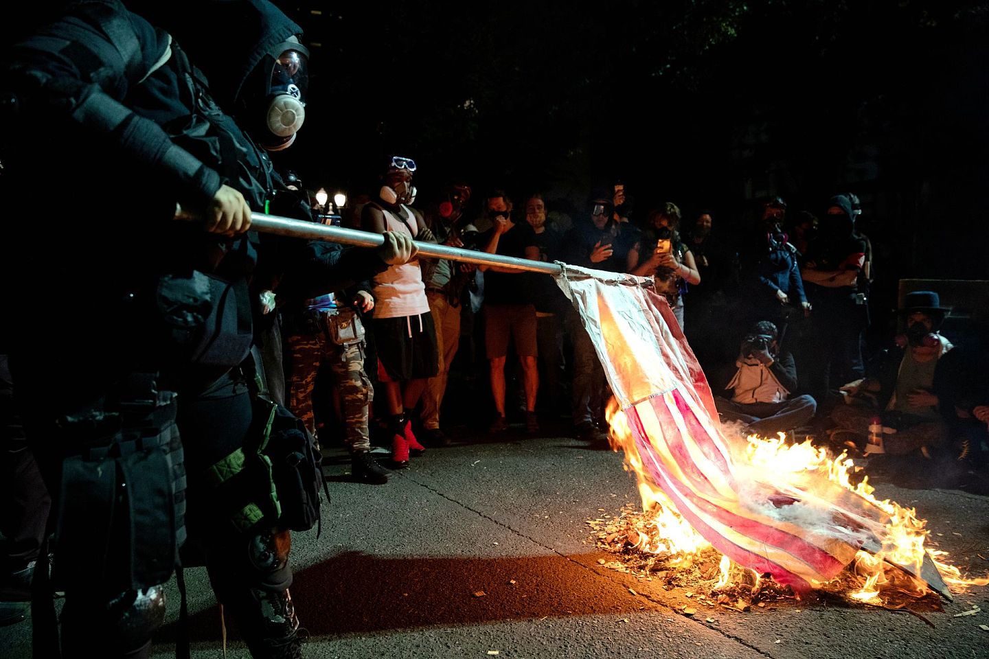 8月1日，俄勒冈州波特兰市，一名抗议者在抗议警察暴力和种族不平等的示威活动中焚烧国旗。（Reuters）