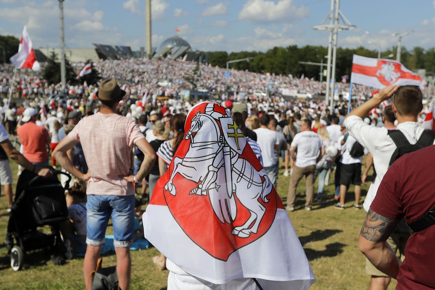 8月16日，一名反政府示威者身披带有盾徽的白罗斯旧国旗。苏联独立后，白罗斯举行全民公投，改用红白旗，直到1995年再度更换。（AP）