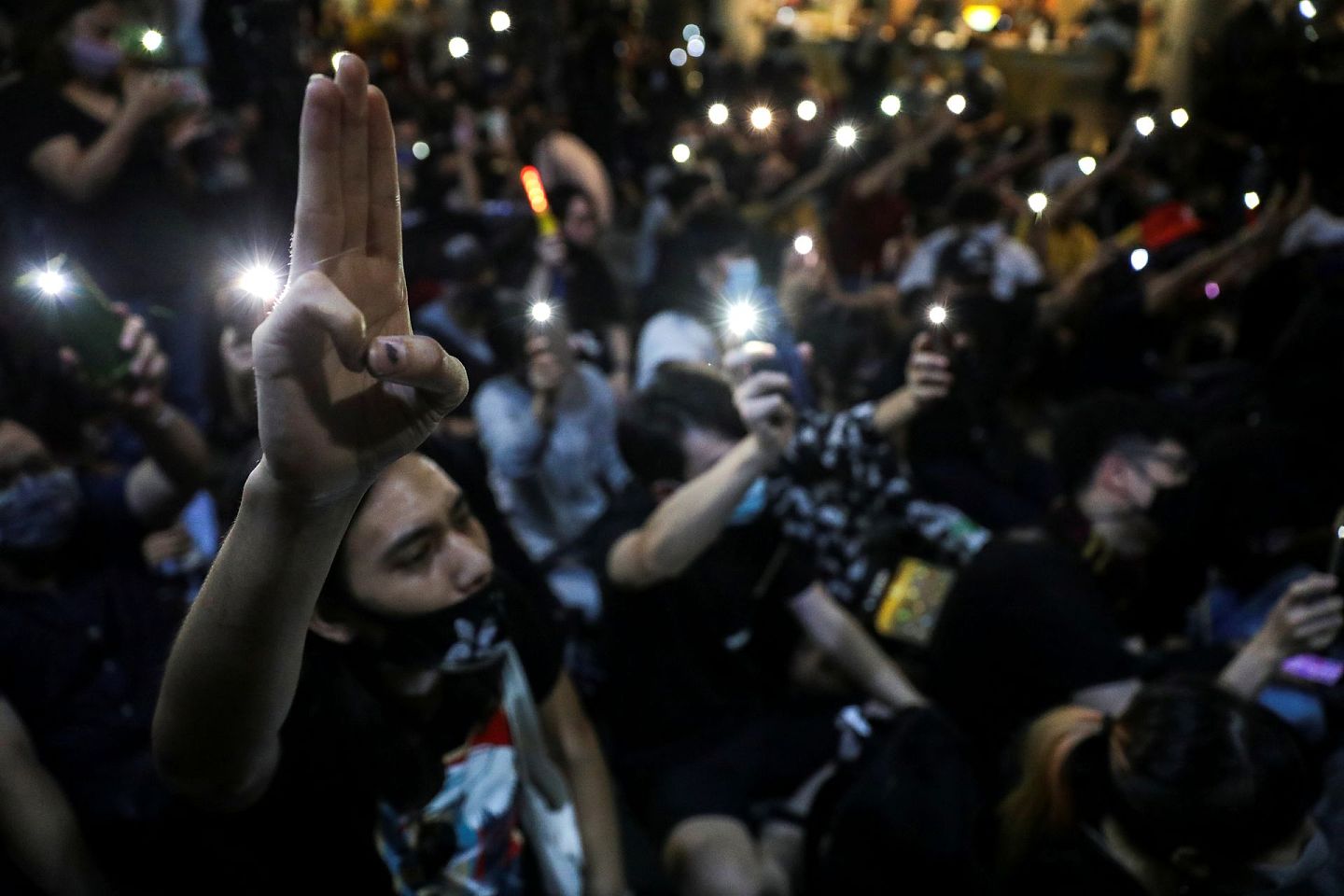 图为2020年8月3日，泰国曼谷有哈利波特主题的示威，要求首相巴育辞职，有示威者举起三根手指，其他人挥动手机的电筒。（Reuters）
