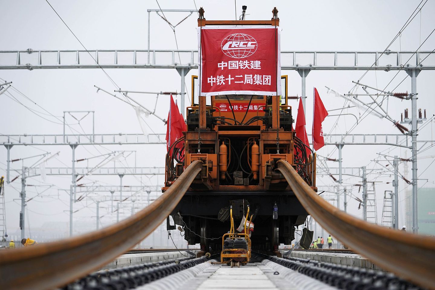 8月17日，中铁十二局的工人驾驶铺轨车在安装最后一段钢轨。（新华社）