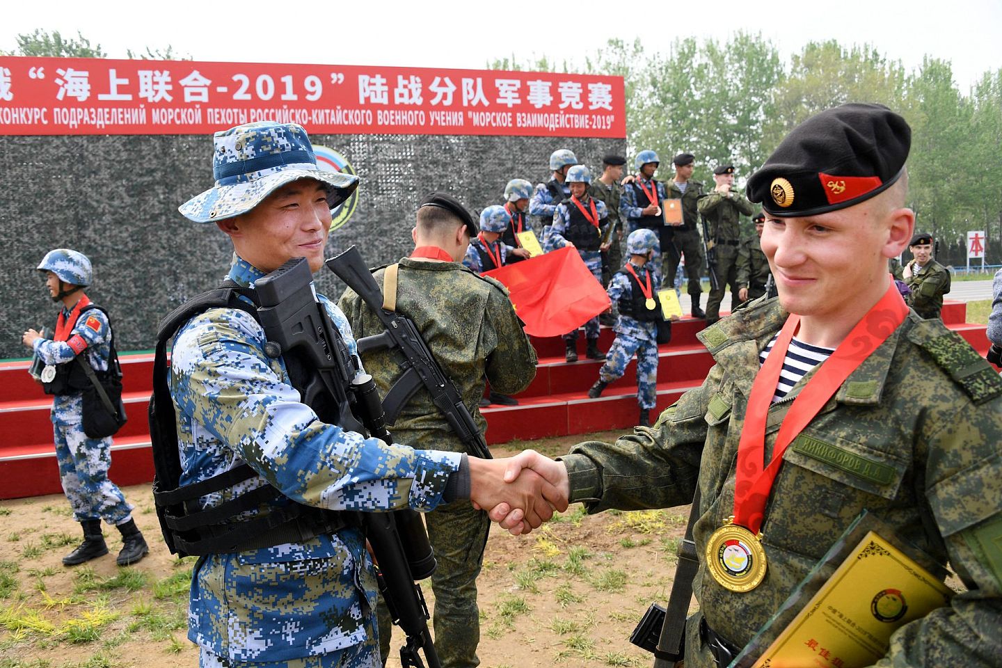 2019年4月30日，中俄“海上联合—2019”军事演习陆战分队军事竞赛举行，图为中俄海军陆战队员在颁奖仪式上握手致意。（ 新华社）