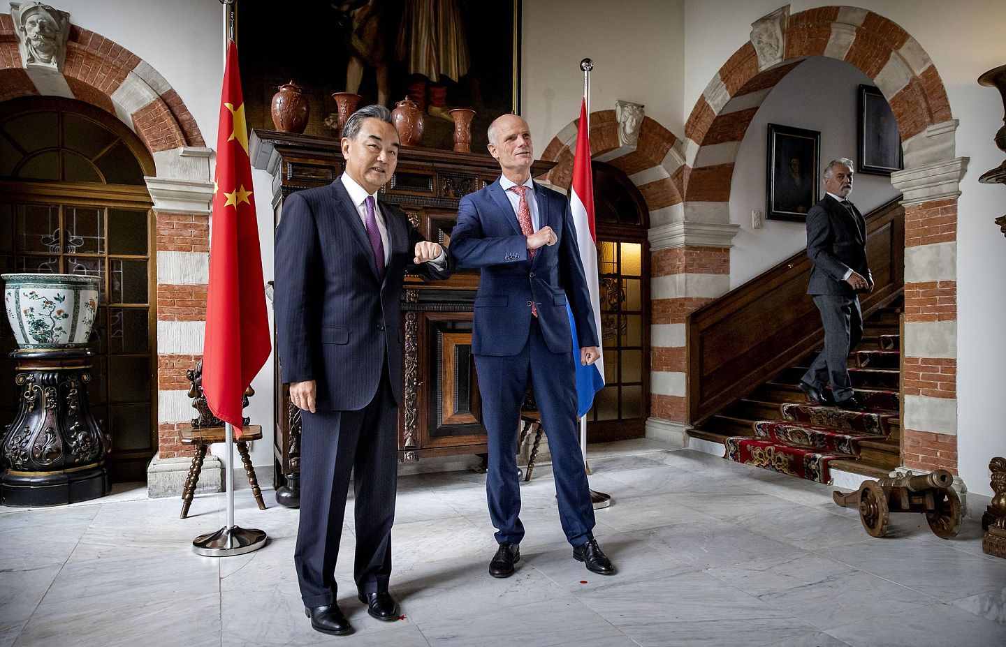 王毅在访问时以击肘代替握手。图为2020年8月26日，王毅访问荷兰，与荷兰外交大臣布洛克会晤。（AP）