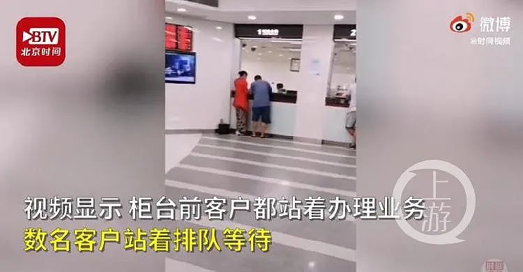 视频显示，有客户站在银行柜台前办理业务，而VIP柜台则有座椅。/北京时间