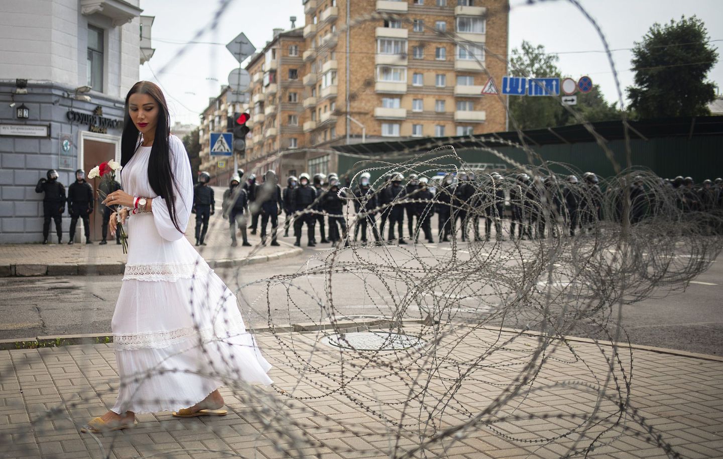 图为8月30日白罗斯反对派的支持者在明斯克发起示威期间，一名女子于隔开军人和支持者的铁丝网旁走过。（AP）