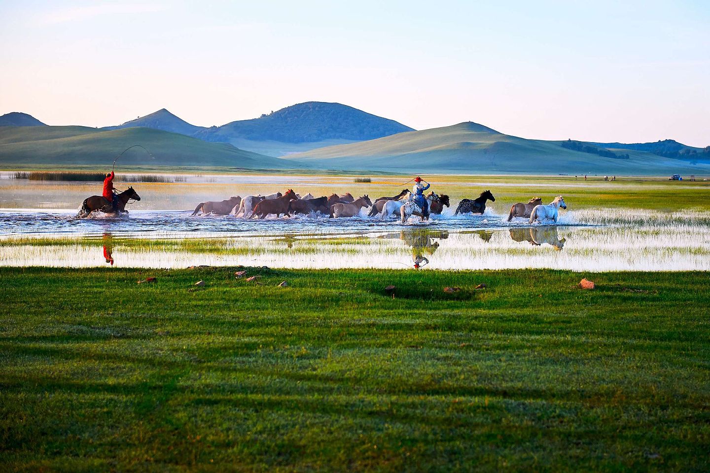内蒙古以广袤的草原著称。图为2016年8月3日内蒙古自治区赤峰市克什克腾旗乌兰布统乡坝上草原日出时分，牧人驱赶马群通过将军泡子。（VCG）