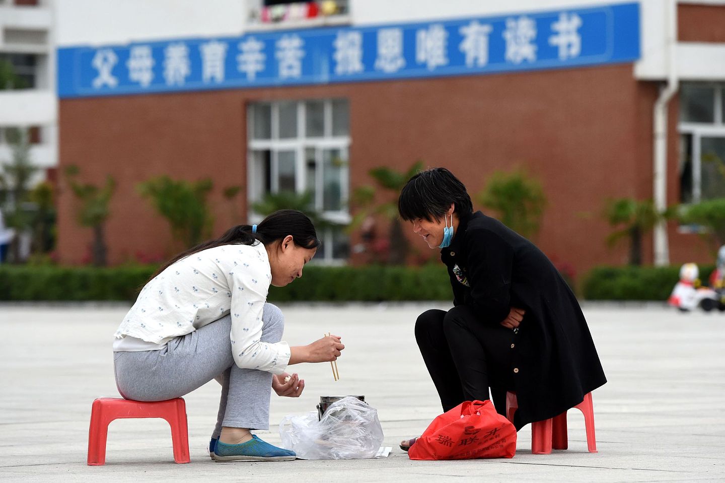 教育是中国人最关注的社会话题之一。图为2016年6月2日在河南省郸城一高校园内，一位家长为孩子送来“加餐”，陪孩子一起吃饭。（新华社）