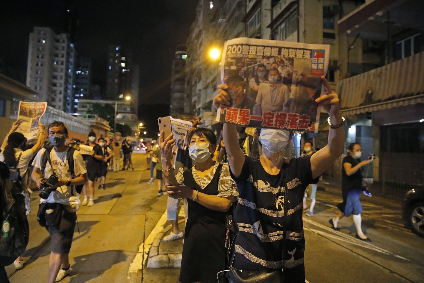 香港壹传媒创办人黎智英在被拘捕一天后获准保释，于当地时间8月12日凌晨时分离开香港旺角警署，黎智英的支持者手持《苹果日报》以示支持。（AP）