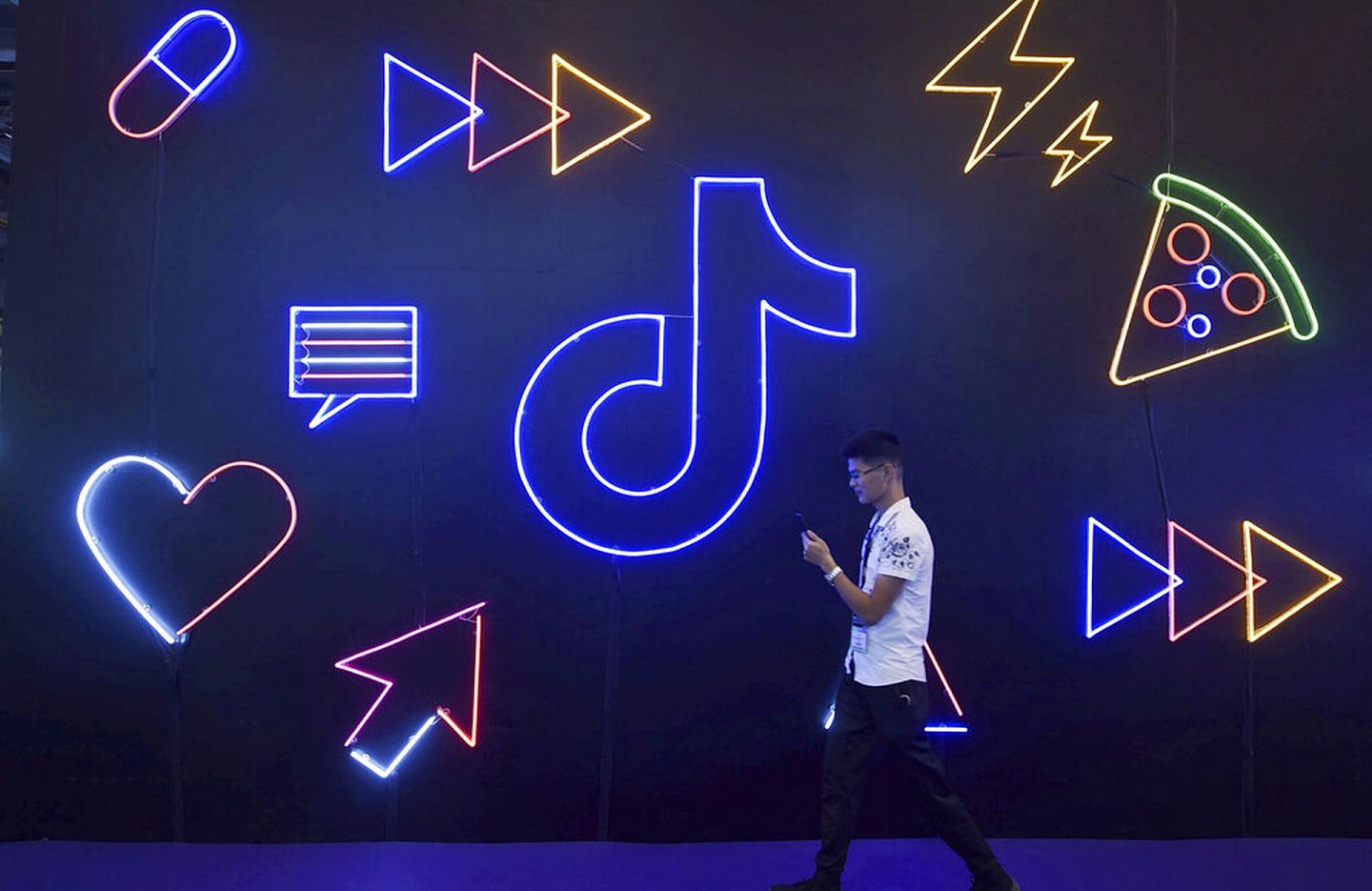TikTok是抖音国际版，在中国与国外拥有众多粉丝。 图为2019年10月18日，一名男子参加在中国杭州市举行的博览会，场内有一个抖音的灯光装置。 （AP）