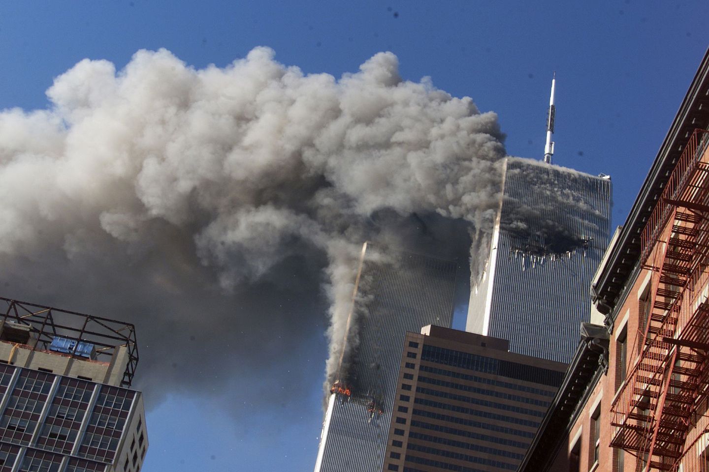 图为2001年“九一一”恐袭发生时令人痛心的一幕：世界贸易中心双子塔分别受袭，冒出大量浓烟，大楼内部分人已心知自己无法逃生。（AP）